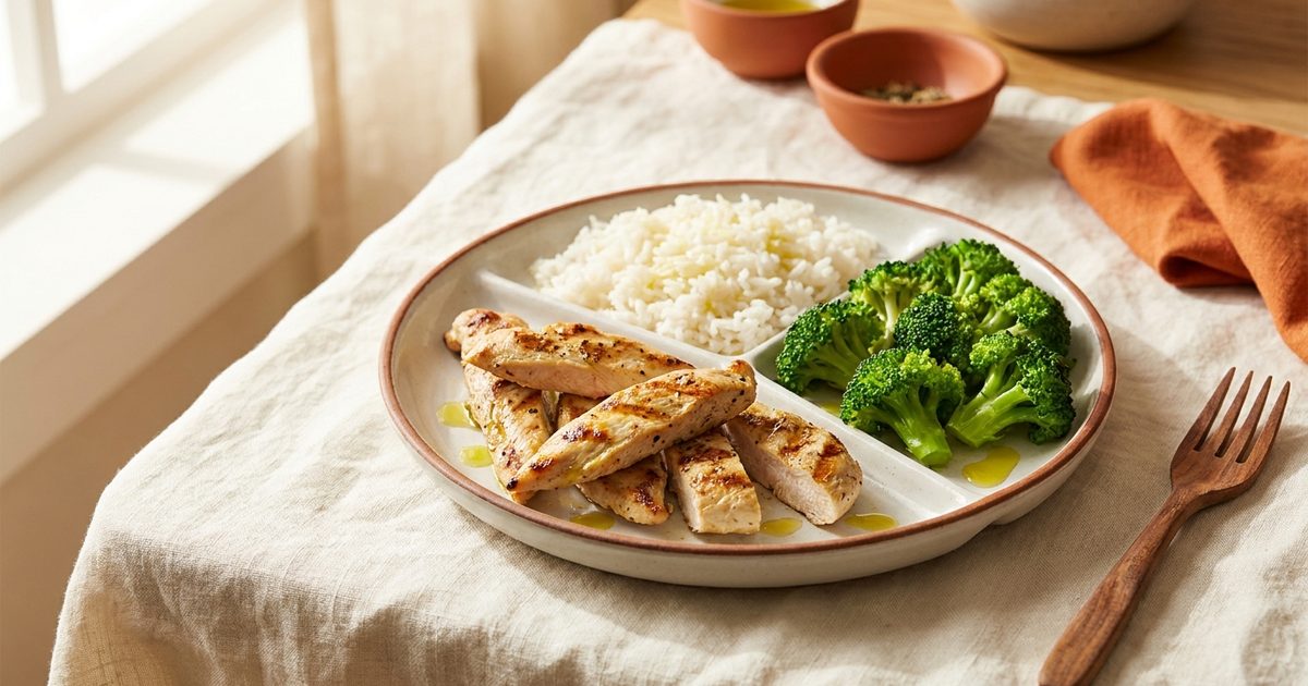 A plate of grilled chicken, rice, and broccoli