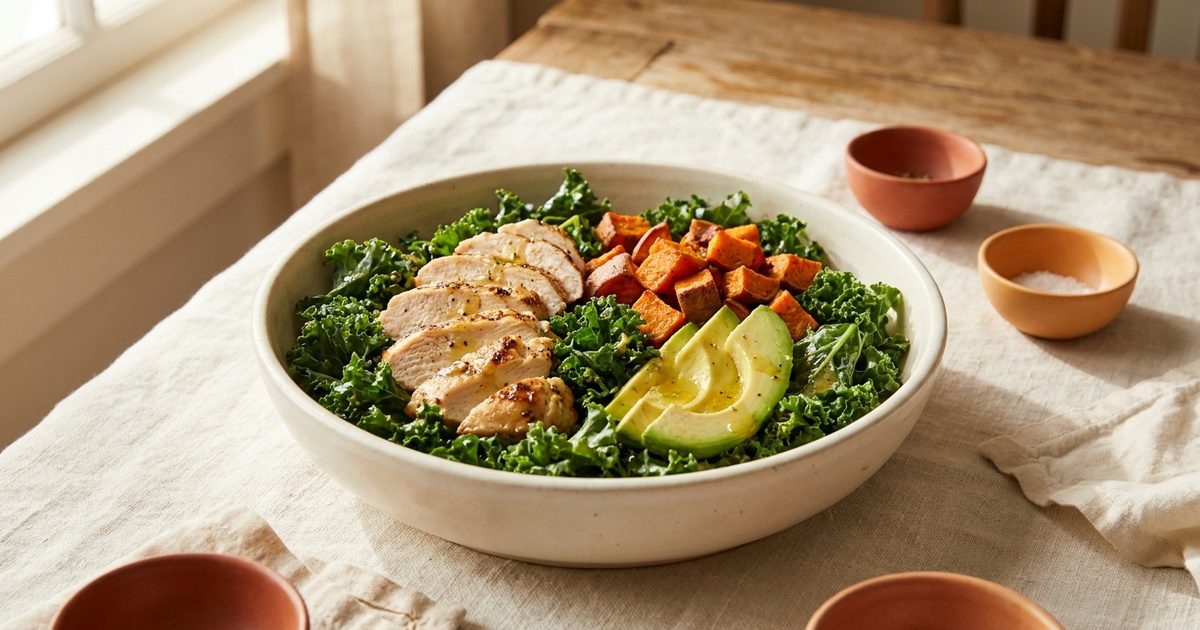 A salad bowl with kale, chicken, sweet potato, and avocado